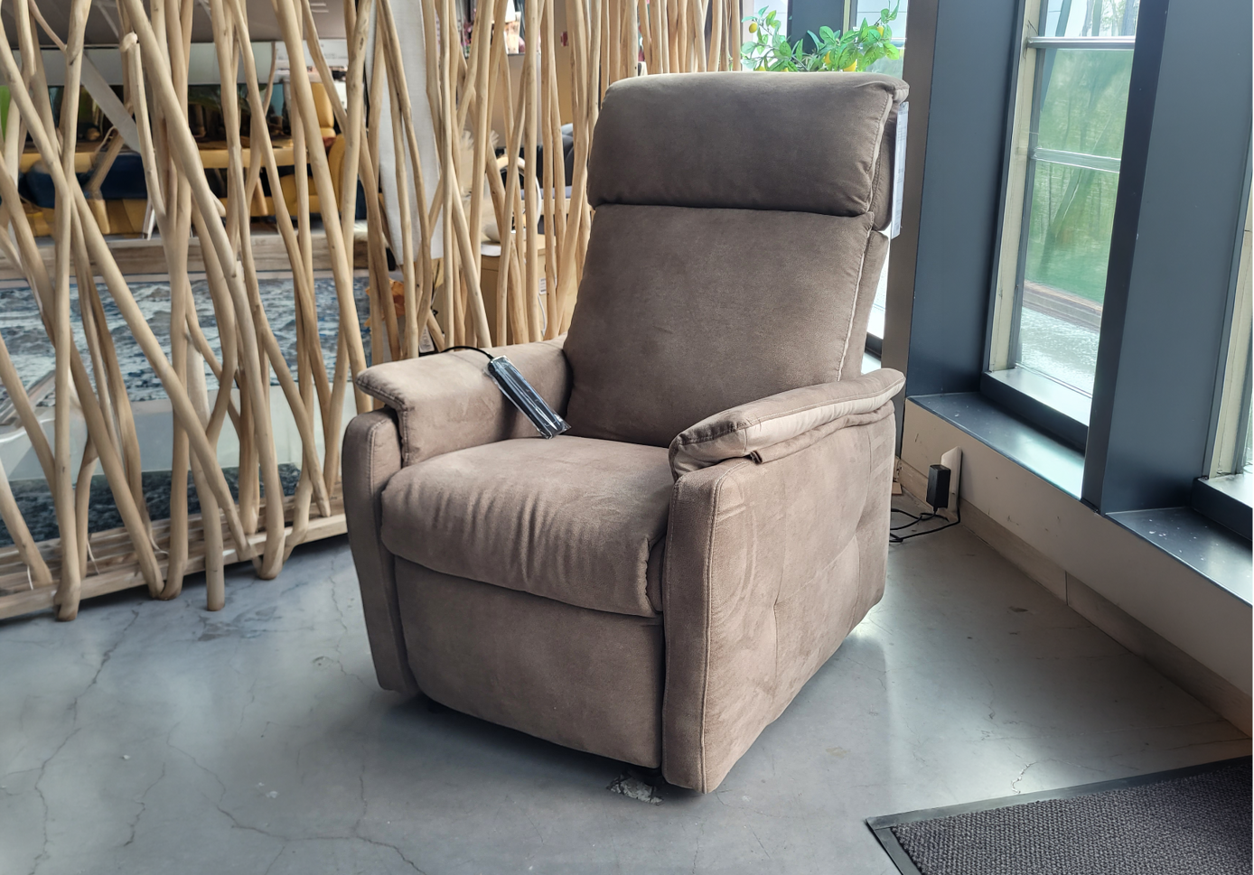 Fauteuil relax en tissu marron clair avec t l commande pos dans un int rieur moderne pr s d'une grande fen tre et d'une cloison en bois d corative.  Description g n r e par IA