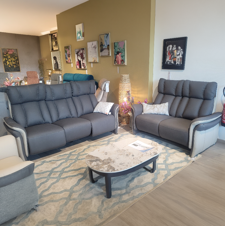 Fauteuil relax gris avec une t l commande pos e sur l'accoudoir dans un int rieur moderne pr s d'une grande fen tre et d'une cloison en bois d corative. Description g n r e par IA