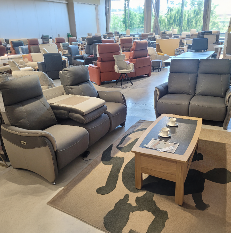 Fauteuil relax gris avec une t l commande pos e sur l'accoudoir dans un int rieur moderne pr s d'une grande fen tre et d'une cloison en bois d corative. Description g n r e par IA