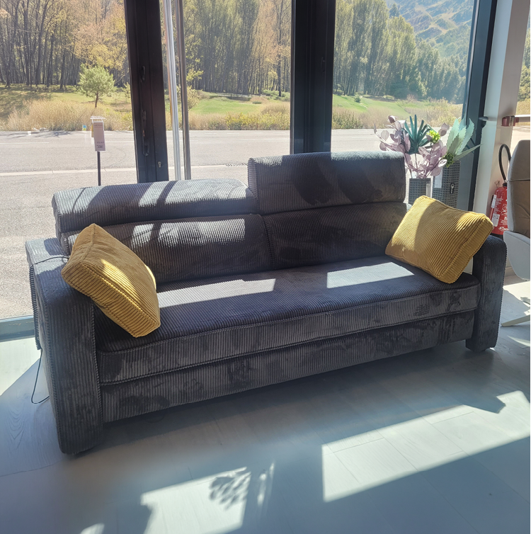 Fauteuil relax gris avec une t l commande pos e sur l'accoudoir dans un int rieur moderne pr s d'une grande fen tre et d'une cloison en bois d corative. Description g n r e par IA