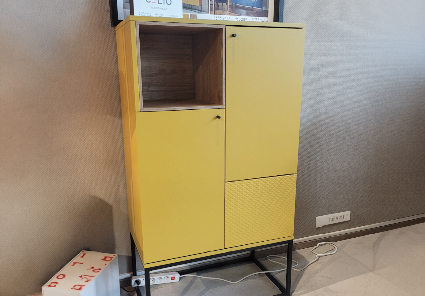 Un meuble de rangement jaune avec une porte ferm e et une niche ouverte est pr sent devant un panneau publicitaire montrant diff rents mod les de meubles.  Description g n r e par IA