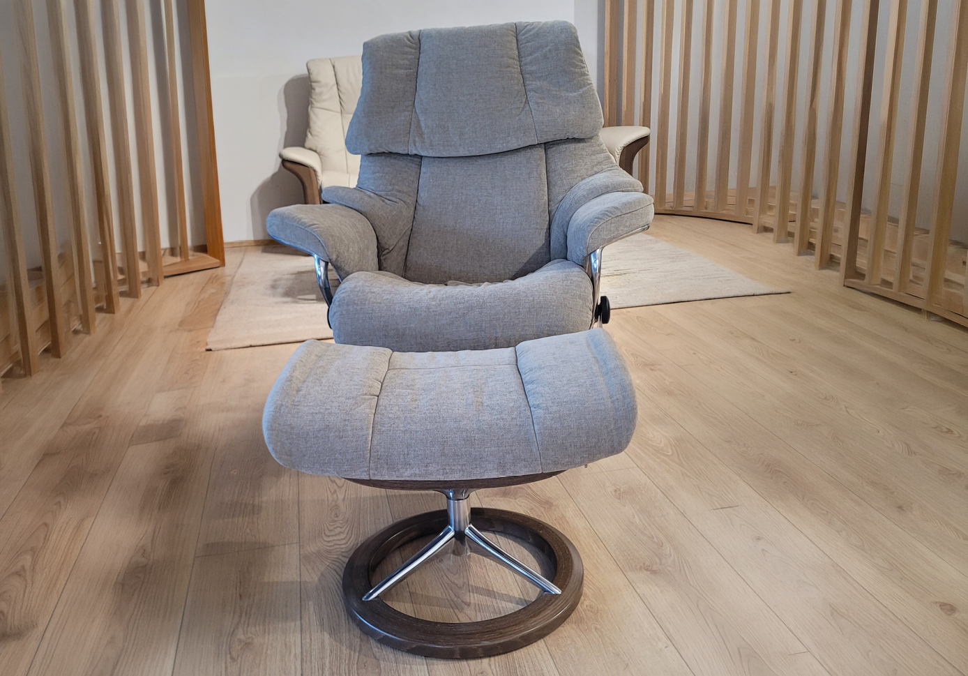 Fauteuil relax gris avec repose-pieds assorti sur un sol en bois clair dans une pi ce avec des cloisons en bois verticales. Description g n r e par IA